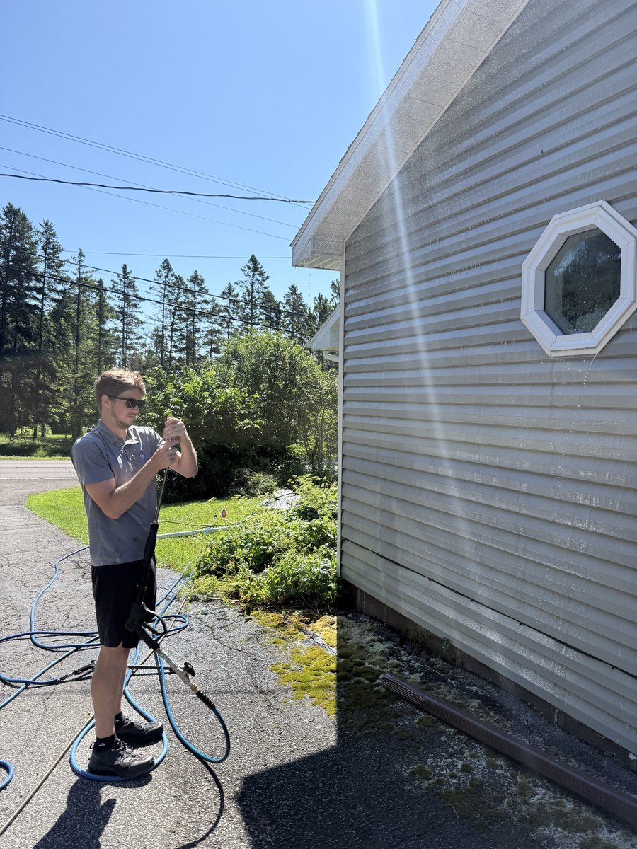Crew member rinsing fresh-washed siding
