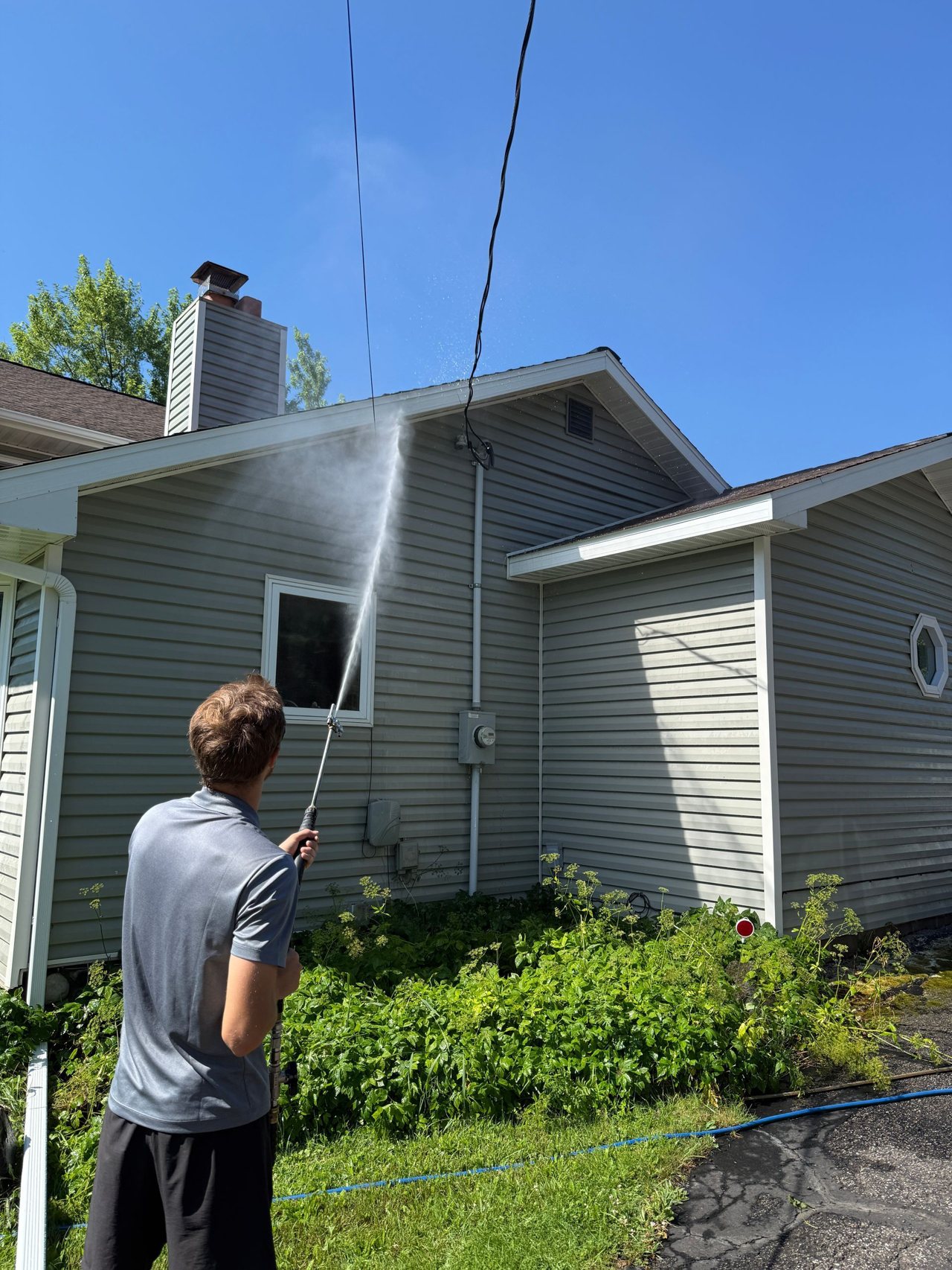 Crew member soft washing the gable end of a North Shore home