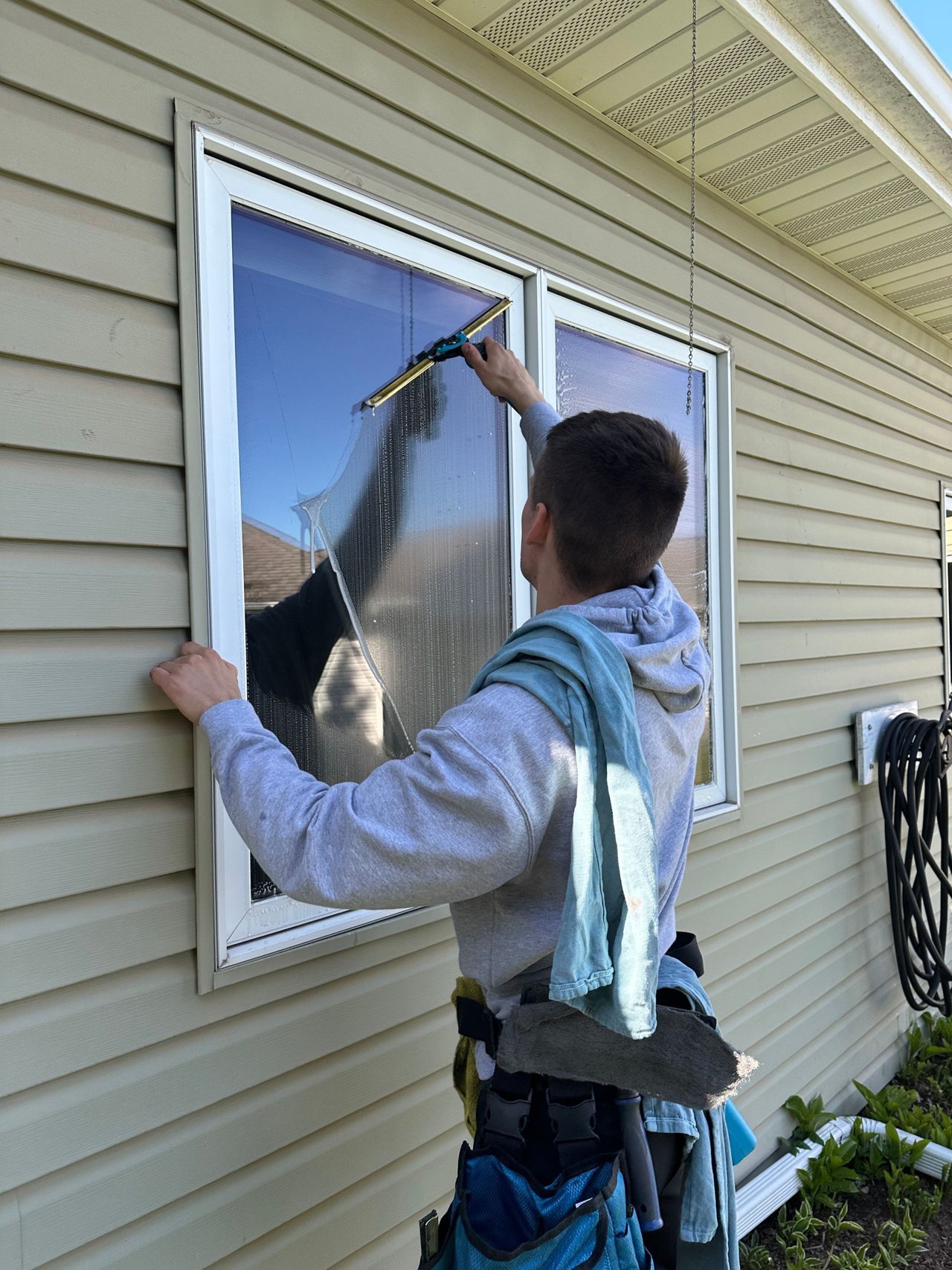 Clear Vue technician hand-cleaning an exterior window on a North Shore home
